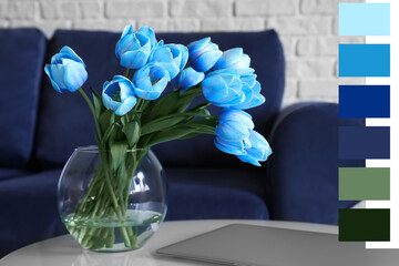 Glass vase with blue tulips and laptop on table in living room. Different color patterns