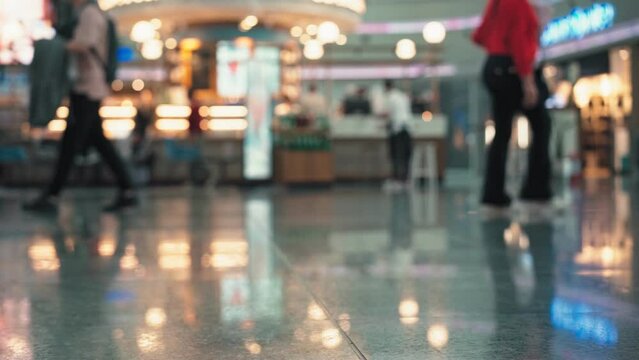 Handheld cinematic defocused footage. Busy airport terminal. People with suitcases walking through the airport.
