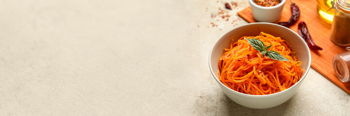 Bowl with spicy Korean carrot salad on grey background with space for text