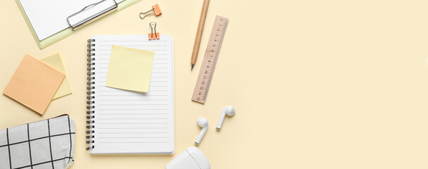 Notebook with stationery and earphones on light color background with space for text