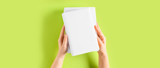 Female hands with blank books on green background