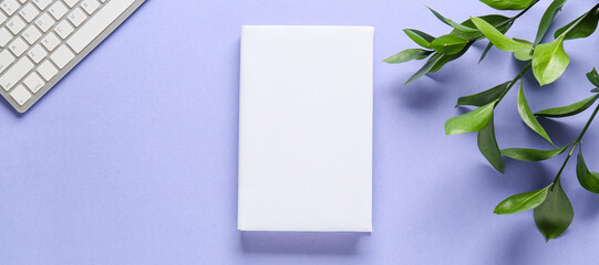 Blank book with computer keyboard and green leaves on color background