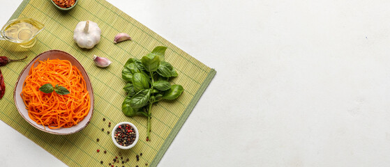 Bowl with spicy Korean carrot salad and ingredients on light background with space for text