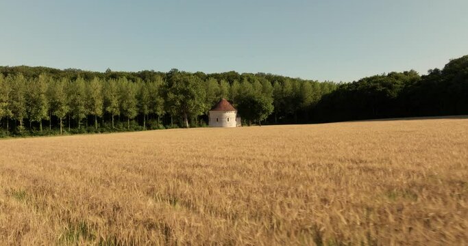Aerial view of the chapel of the Liget next to wheat fields during sunset in France.