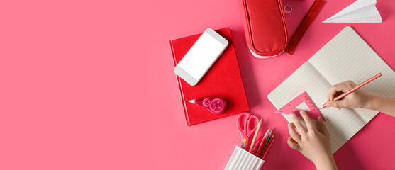 Child's hands with stationery and mobile phone on pink background with space for text