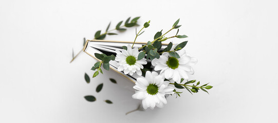 Book with fresh flowers on white background, top view