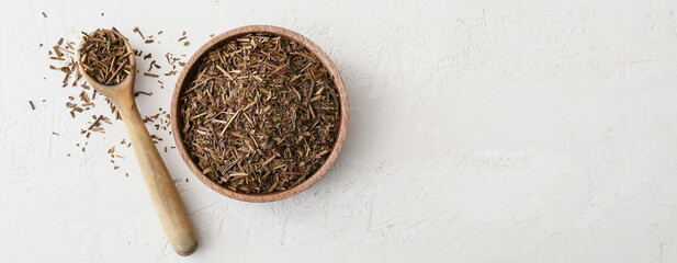 Bowl and spoon with dry hojicha green tea on light background with space for text