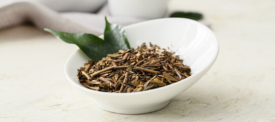 Fototapeta premium Bowl of dry hojicha green tea on light background