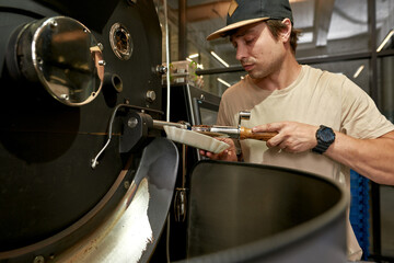 Male worker check coffee beans on roasting machine