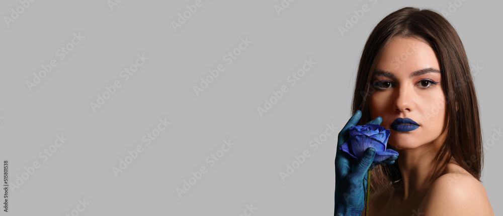 Poster Stylish young woman with painted hand, blue lipstick and rose on grey background with space for text