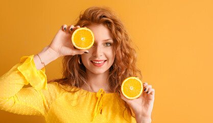 Beautiful young redhead woman with cut orange on color background