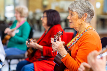 a colourful group of senior women playing ukulele