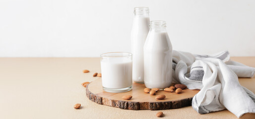 Bottles and glass of tasty almond milk on table