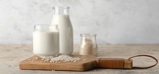 Glass and bottle of tasty rice milk on light background