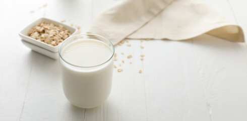 Glass of tasty oat milk on white table