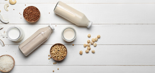 Fototapeta na wymiar Different vegan milks on white wooden background with space for text