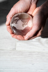 Close-up of female hands with a crystal globe on a woody background.
