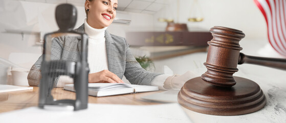Double exposure of female notary public working in office and judge's gavel on table