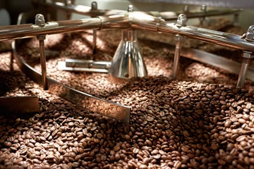 Tuinposter Natural roast coffee beans mixing in roast machine © Svitlana