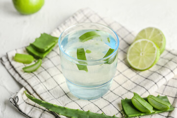 Glass of aloe juice with lime on white background