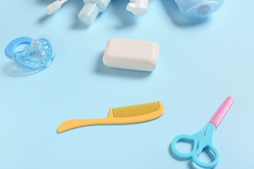 Hair comb, scissors, bar of soap and pacifier on blue background, closeup