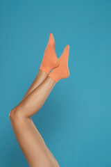 Pretty female legs in orange short socks, on a blue background