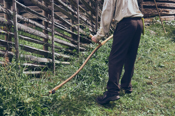 a man cuts a meadow with a scythe