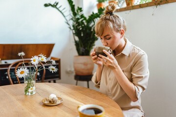 A young girl sits at a table in a coffee shop and drinks coffee. Stylish coffee shop