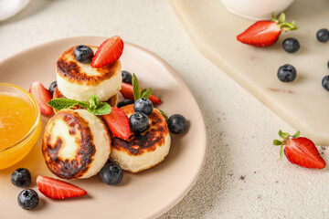 Delicious cottage cheese pancakes with berries and mint leaves served on white table, closeup