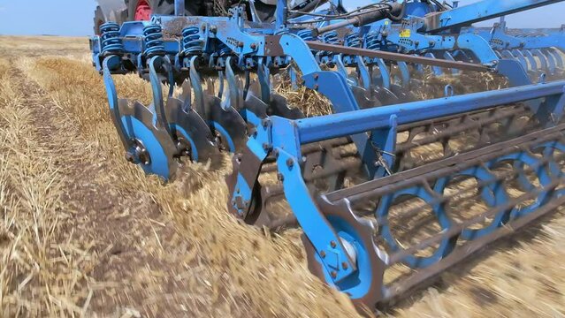 Close-up of a rotary cultivator and a disc plow on a tractor while working in the field. Removing the crust, loosening and aerating the soil in the autumn. Soil preparation before sowing winter crops