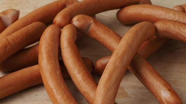 Thin long pork sausages on the wooden cutting board