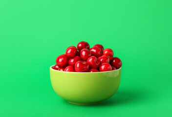 Bowl of sweet cherries on green background