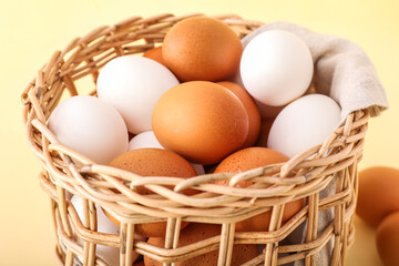Wicker basket with chicken eggs on color background, closeup