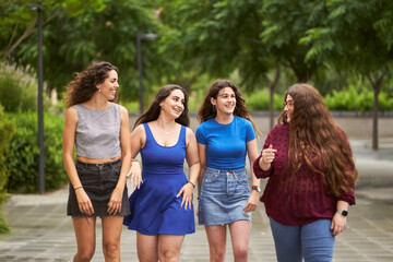 Group of friends talking while walking through a park when it is starting to rain, concept friendship