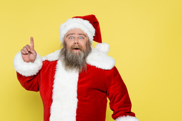 excited overweight santa claus showing idea sign and looking at camera isolated on yellow.