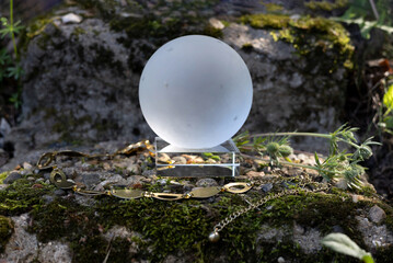 Glass magic ball stands on old mossy stone, next to  chain, attributes for divination, selective...