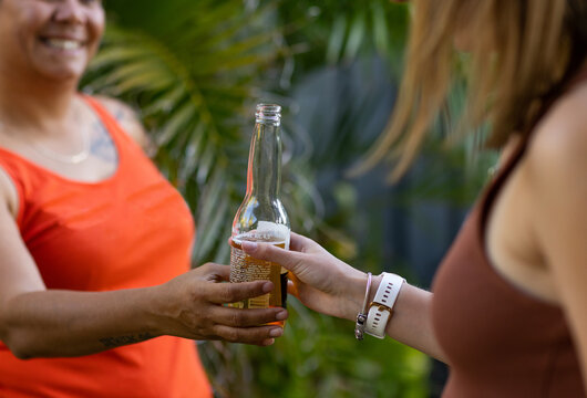 two women sharing a bottle of beer