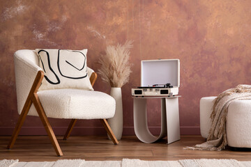 The stylish composition a living room interior with white armchair, pouf, gramophone, vase with dried flowers and personal accessories. Home decor. Template.