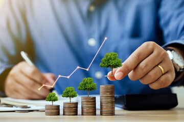 Saving money and investment concept. Businessmen put a coin with a tree that grows and a tree that...
