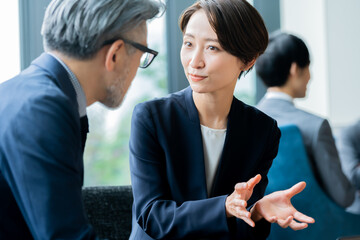 ビルの窓際に座り話す複数のかっこいいビジネスマン
