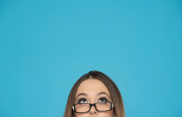 half portrait of a young woman with glasses looking up on a blue background