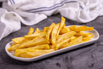 Fried potatoes. French fries on dark background. French fries served on a plate. close up
