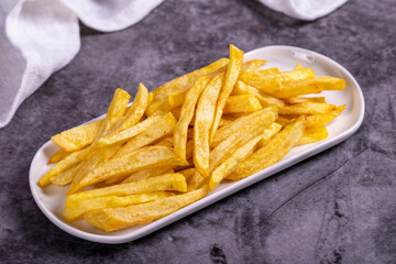 Fried potatoes. French fries on dark background. French fries served on a plate. close up