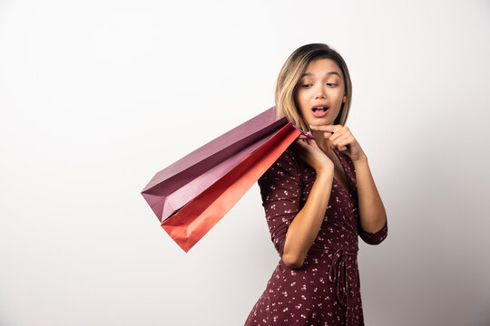 Young woman holding shop bags on white background