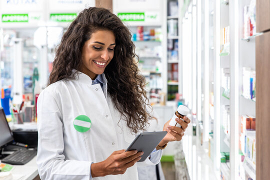 Female Pharmacist Working In Pharmacy Using Digital Tablet During Inventory.