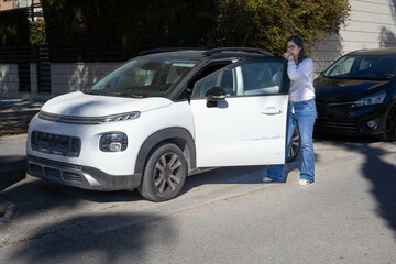 Woman thinking about the damage in her car, done while it was parked in the street. She has a good car insurance, and she knows that the company will take care of the situation.