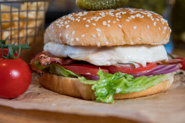 Burger with chicken breast, lettuce leaves, tomatoes, pickles and hot peppers