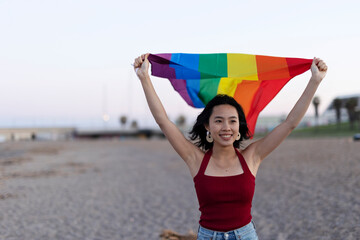 Happy girl with a pride flag at the beach. LGBT community