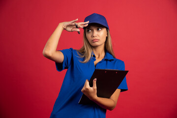 Young woman in blue uniform holding clipboard with pencil