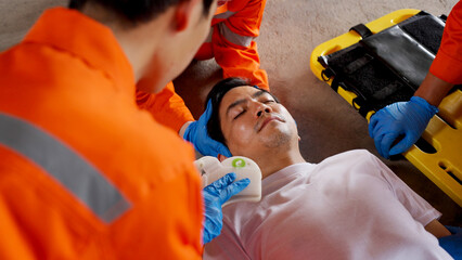 Asian emergency medical technician (EMT) or paramedic team is holding manual stabilization of the...